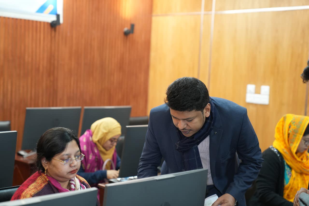 Raihan Khan guides women participants seated at their computer terminals during a hands-on training exercise.