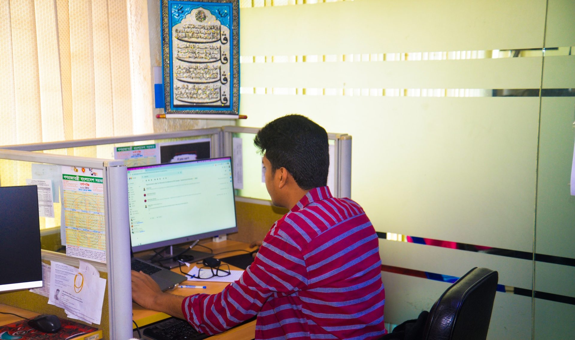 Raihan Khan reviewing emails at his office desk inside an MTI Ltd. cubicle.