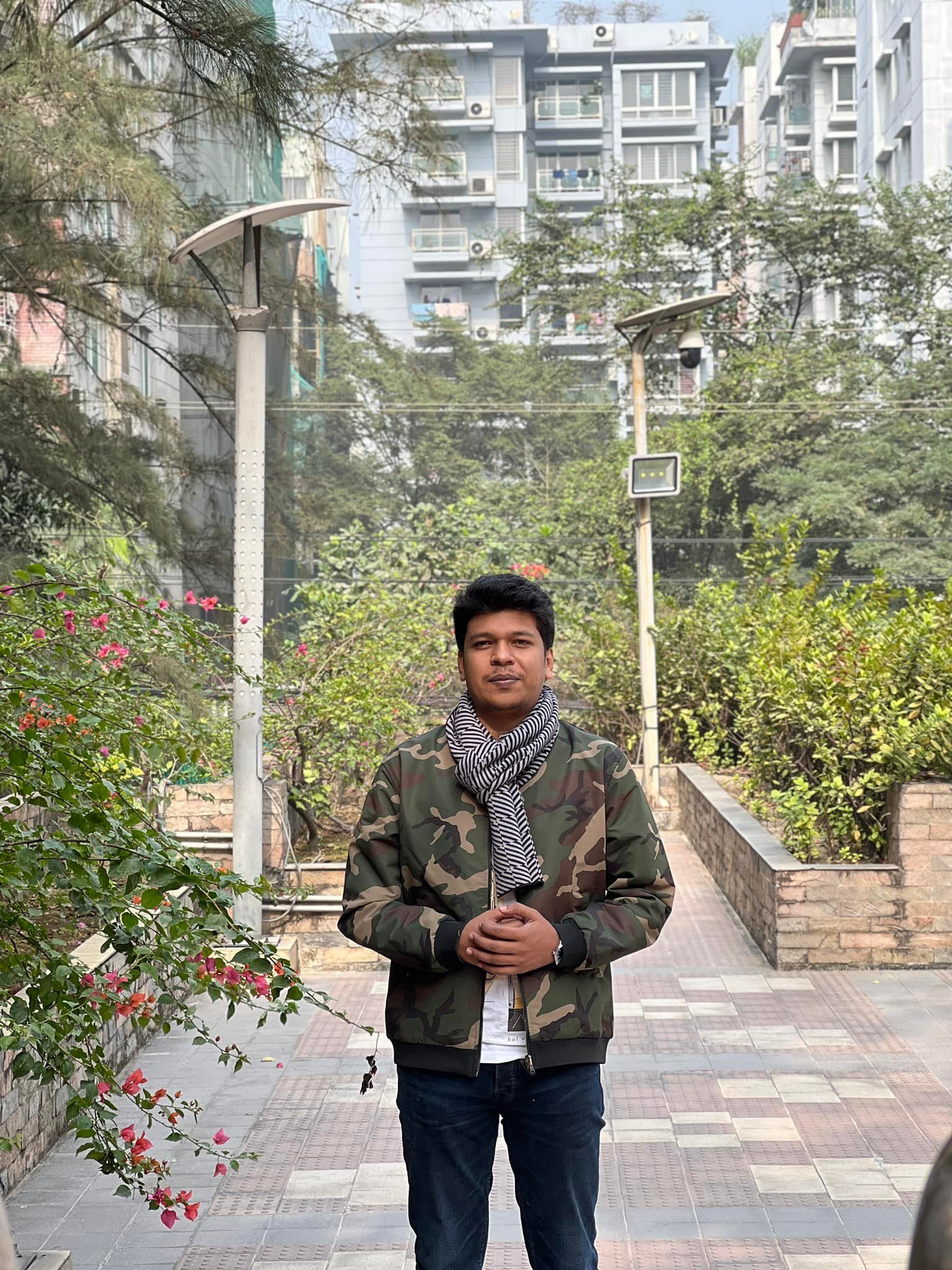 Raihan Khan walking past blooming bougainvillea bushes on a campus footpath.