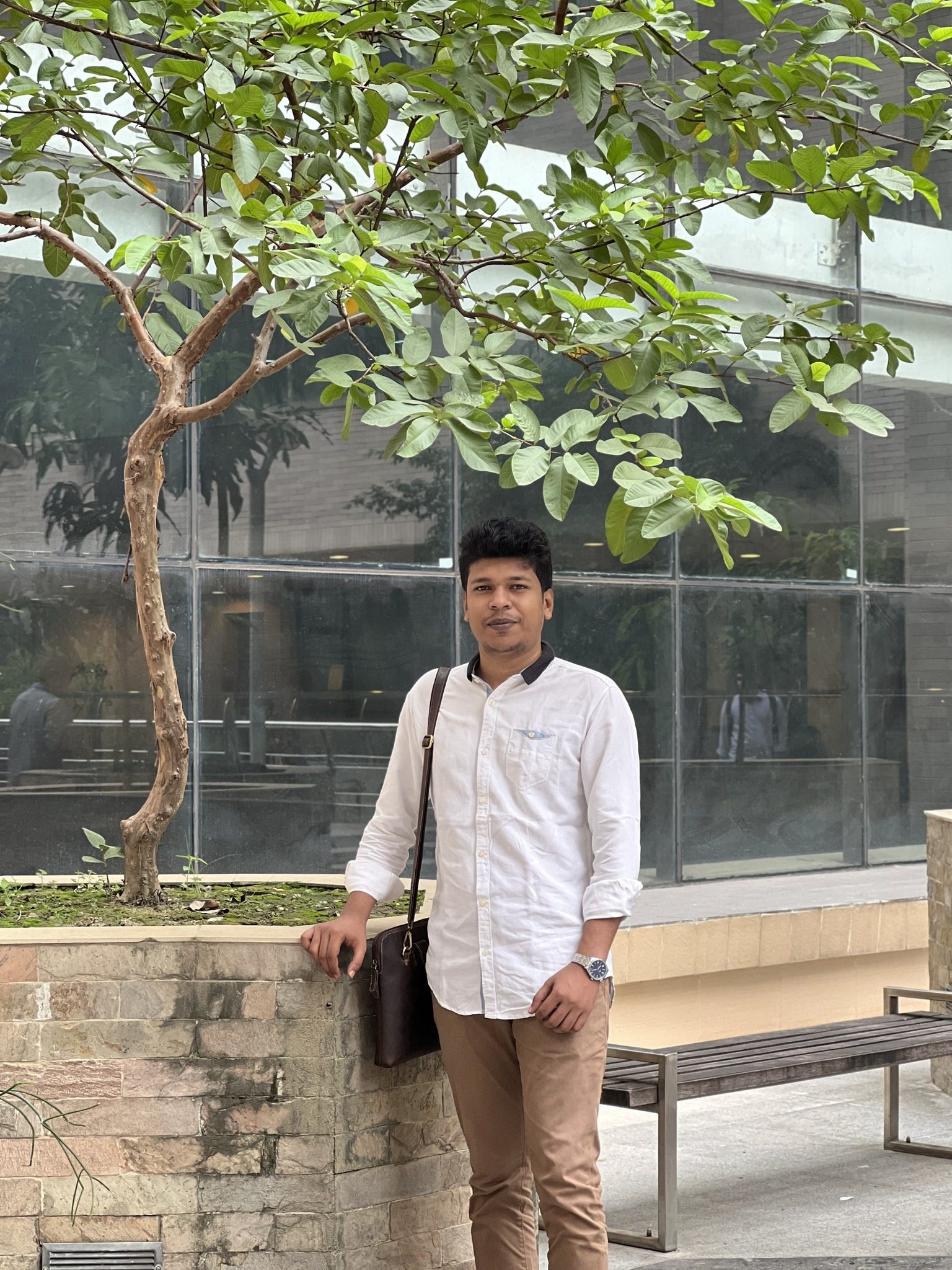 Raihan Khan standing beside a guava tree in a quiet courtyard at NSU.