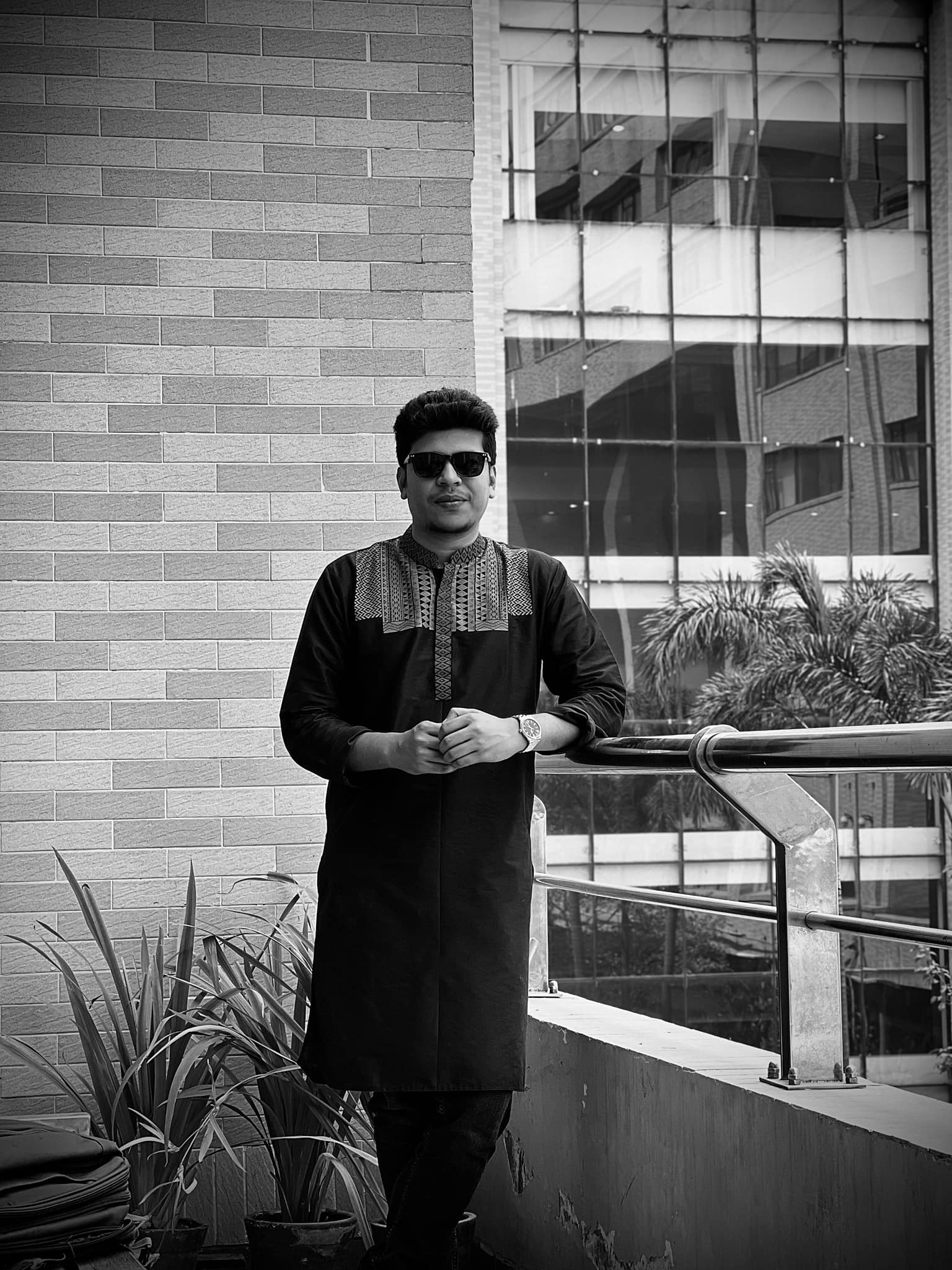 A black and white portrait of Raihan Khan leaning on a balcony railing at North South University.