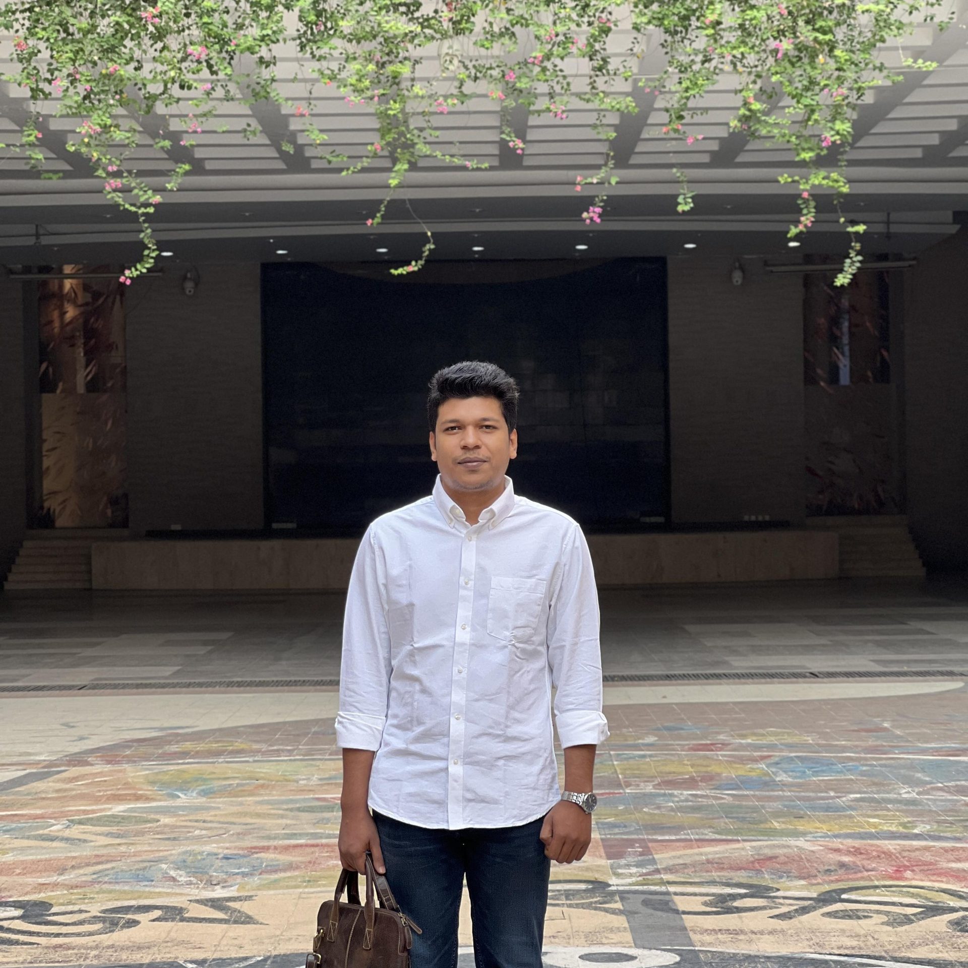 Raihan Khan standing on a colorful mosaic plaza beneath a flowering pergola at NSU.