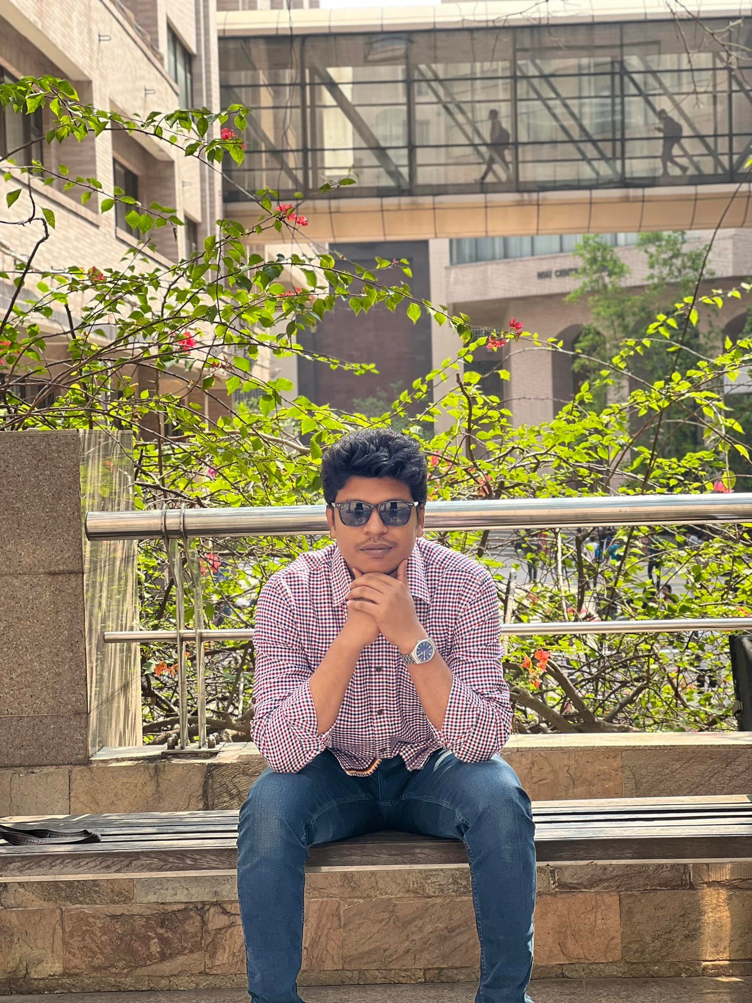 Raihan Khan sitting on a bench in a thoughtful pose with his chin resting on his hand.