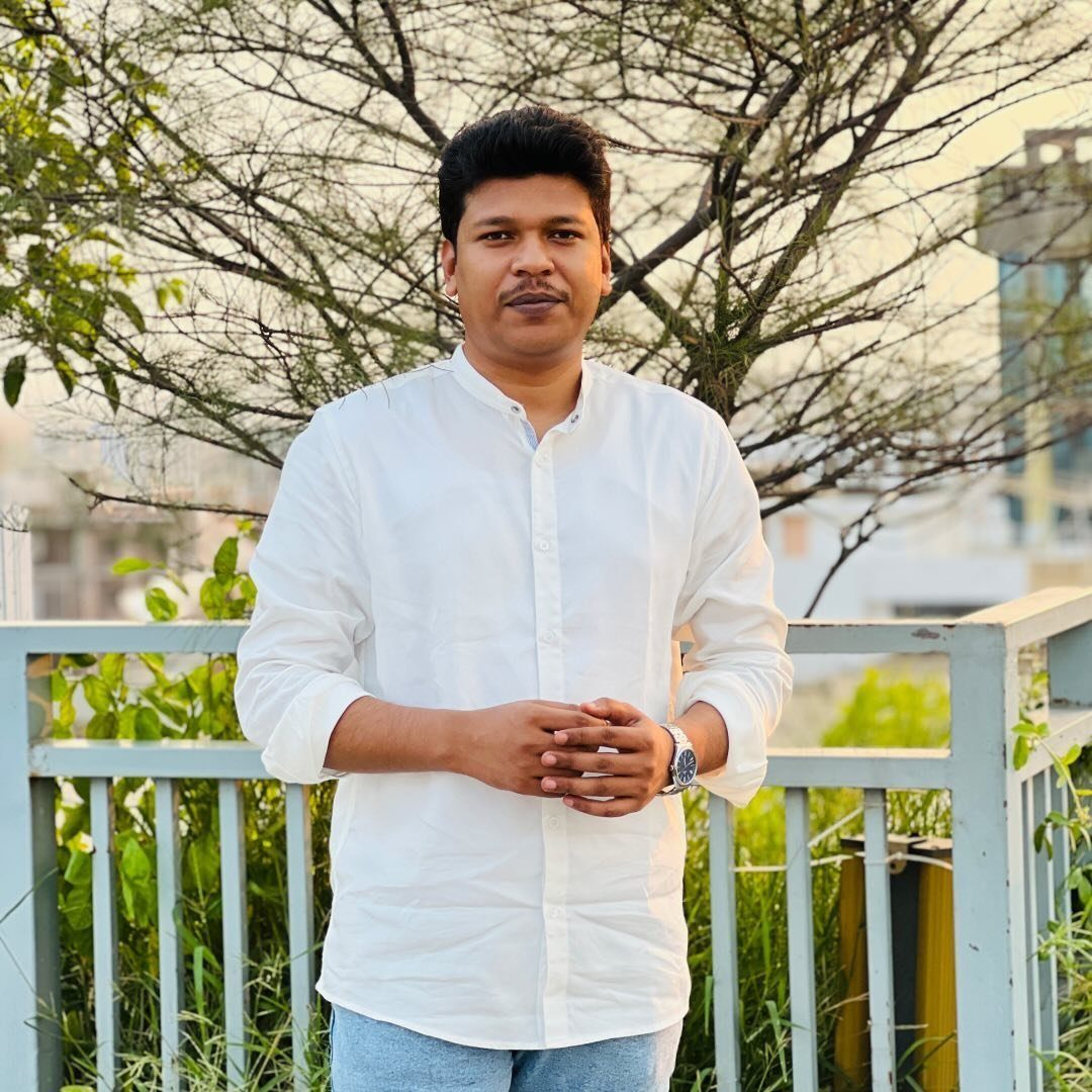 Raihan Khan in a white mandarin-collar shirt standing on a rooftop against bare tree branches.