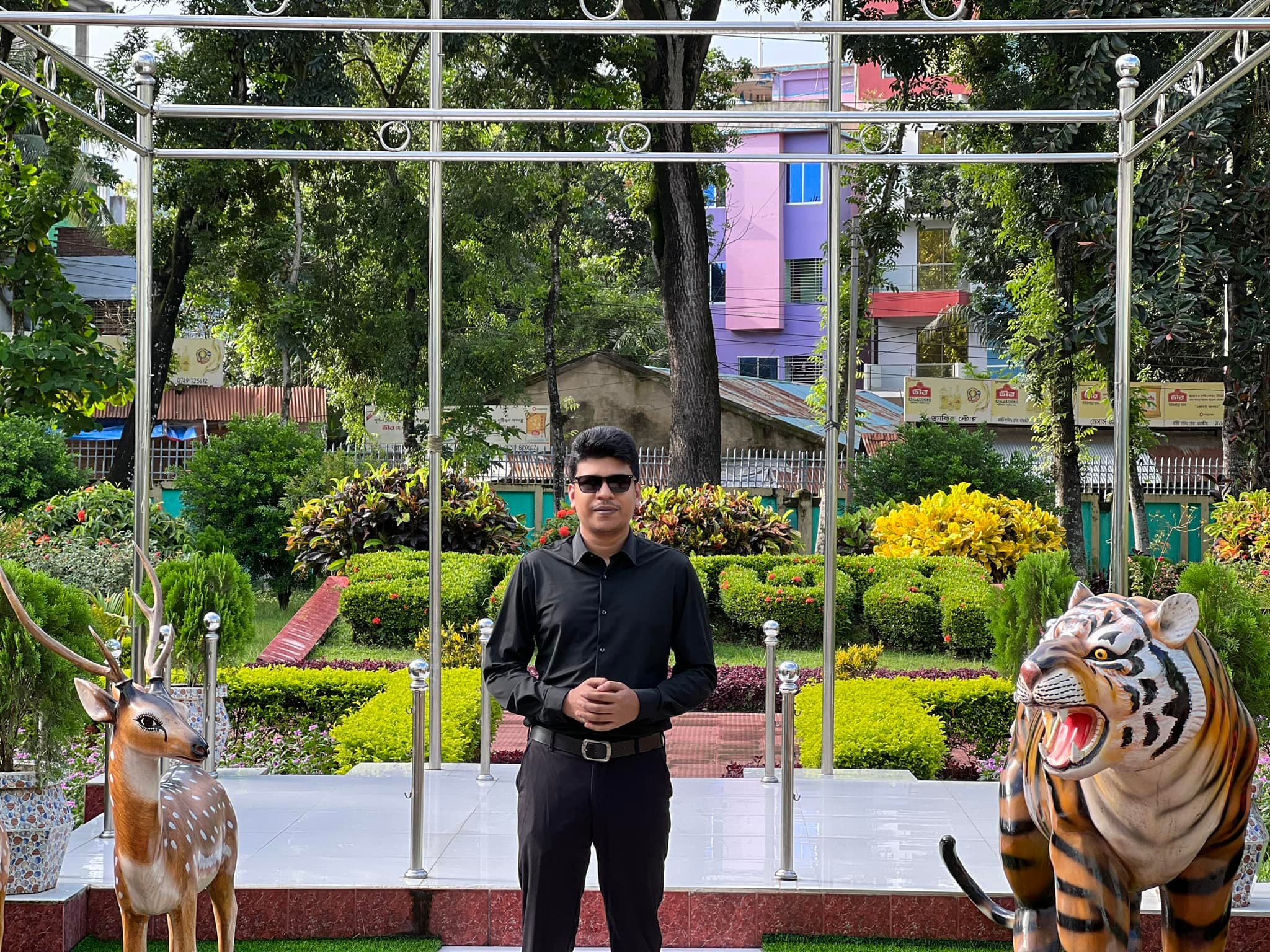 Raihan Khan sitting near carved deer and tiger statues in a themed garden park.