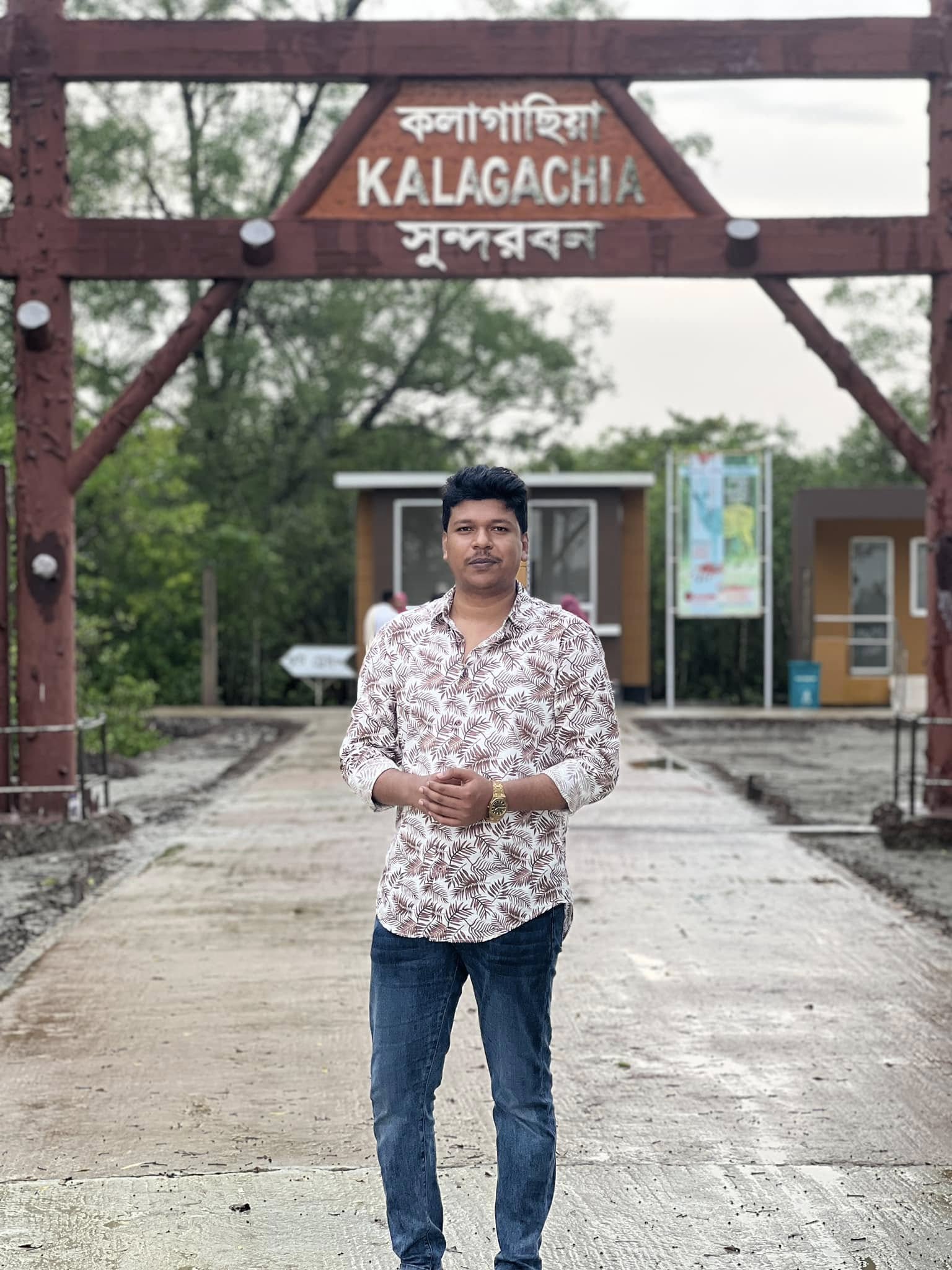 Raihan Khan standing at the wooden entrance gate to the Kalagachia Sundarbans forest station.