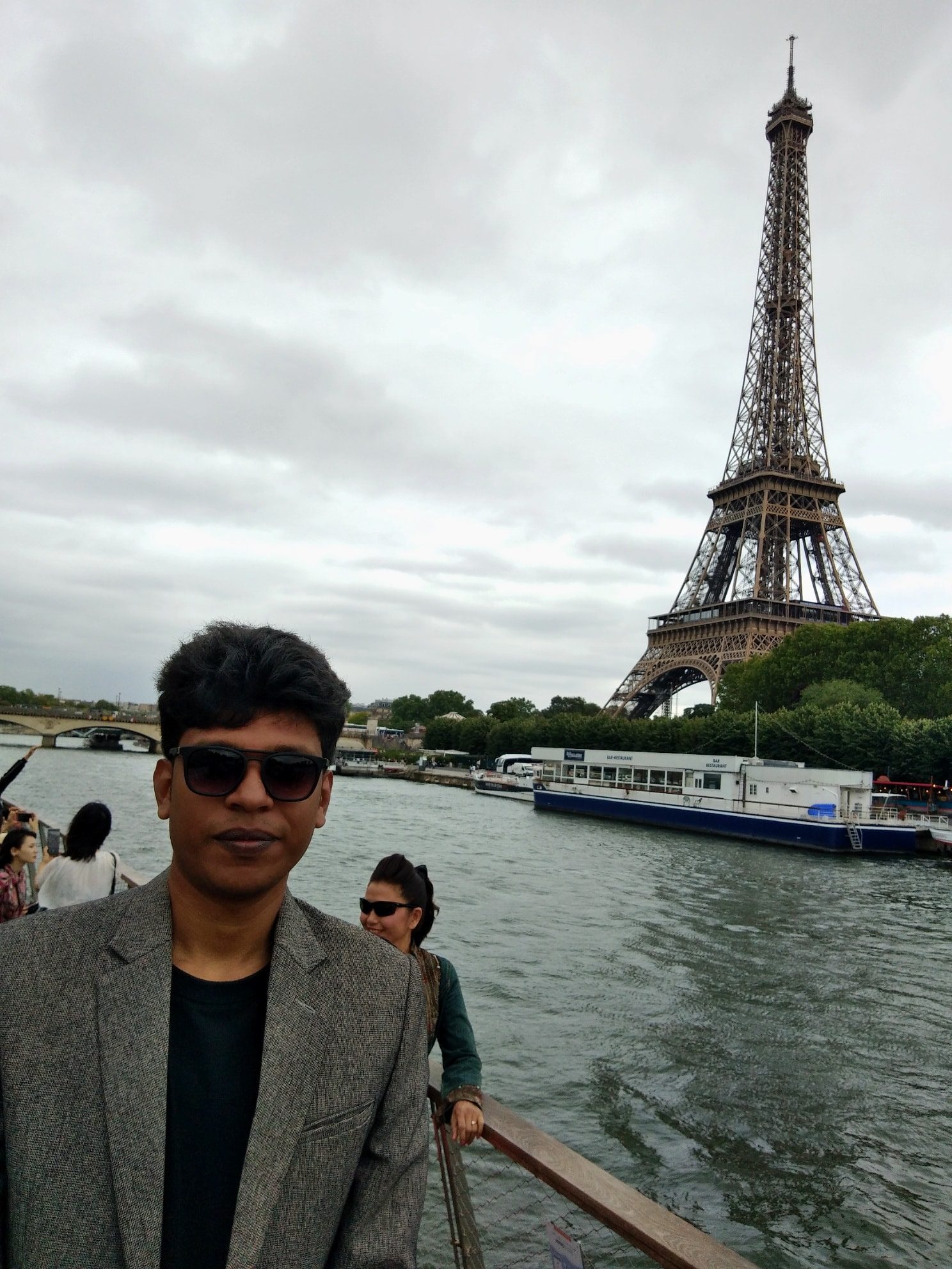 Raihan Khan on a Seine river cruise boat with the Eiffel Tower visible in the background.