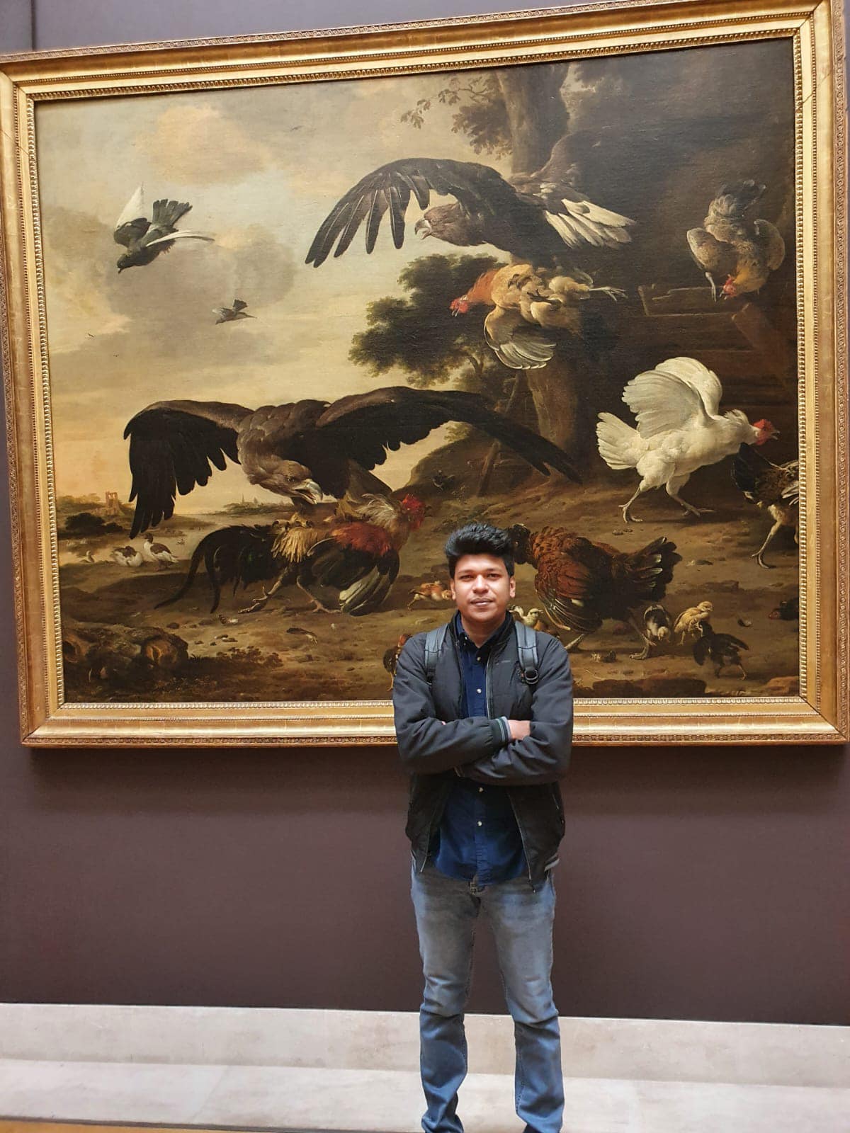 Raihan Khan standing in front of a large classical painting of birds inside the Louvre Museum.