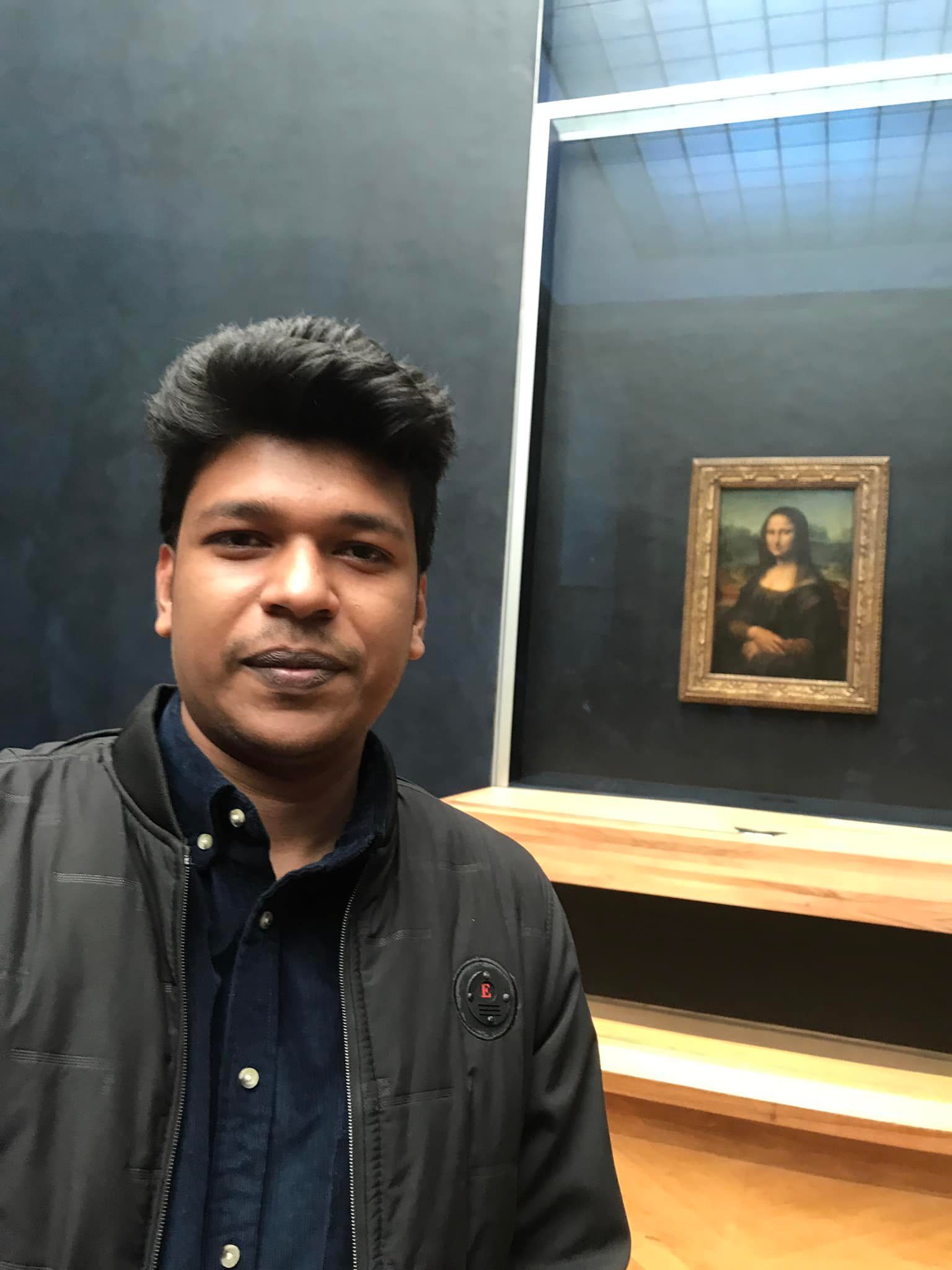 Raihan Khan taking a selfie with the Mona Lisa painting on display at the Louvre Museum.