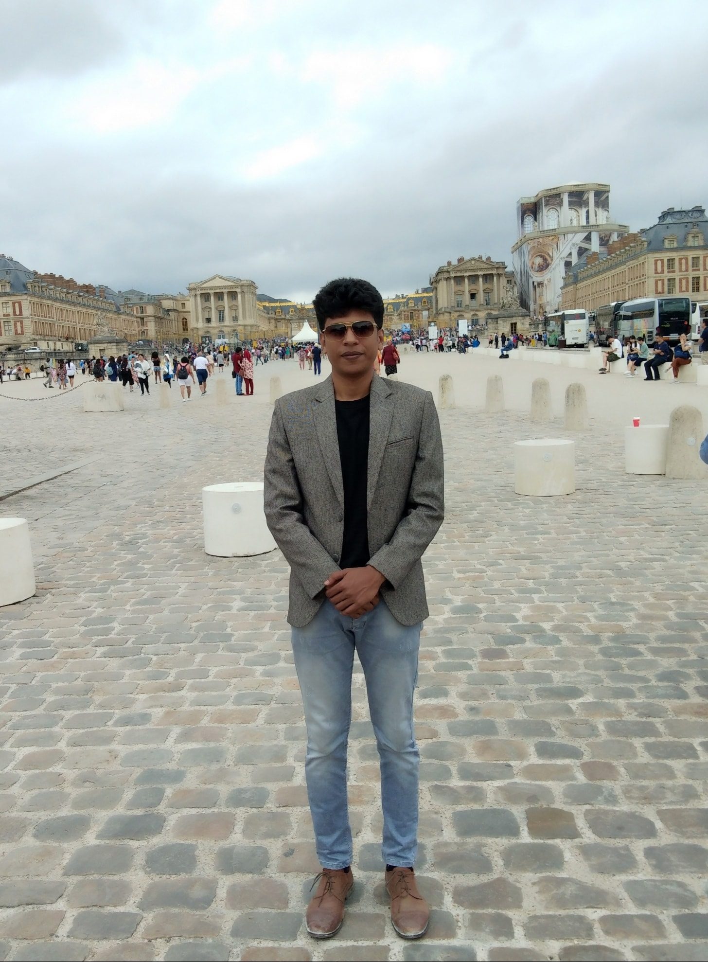 Raihan Khan standing in the cobblestone courtyard of the Palace of Versailles in France.