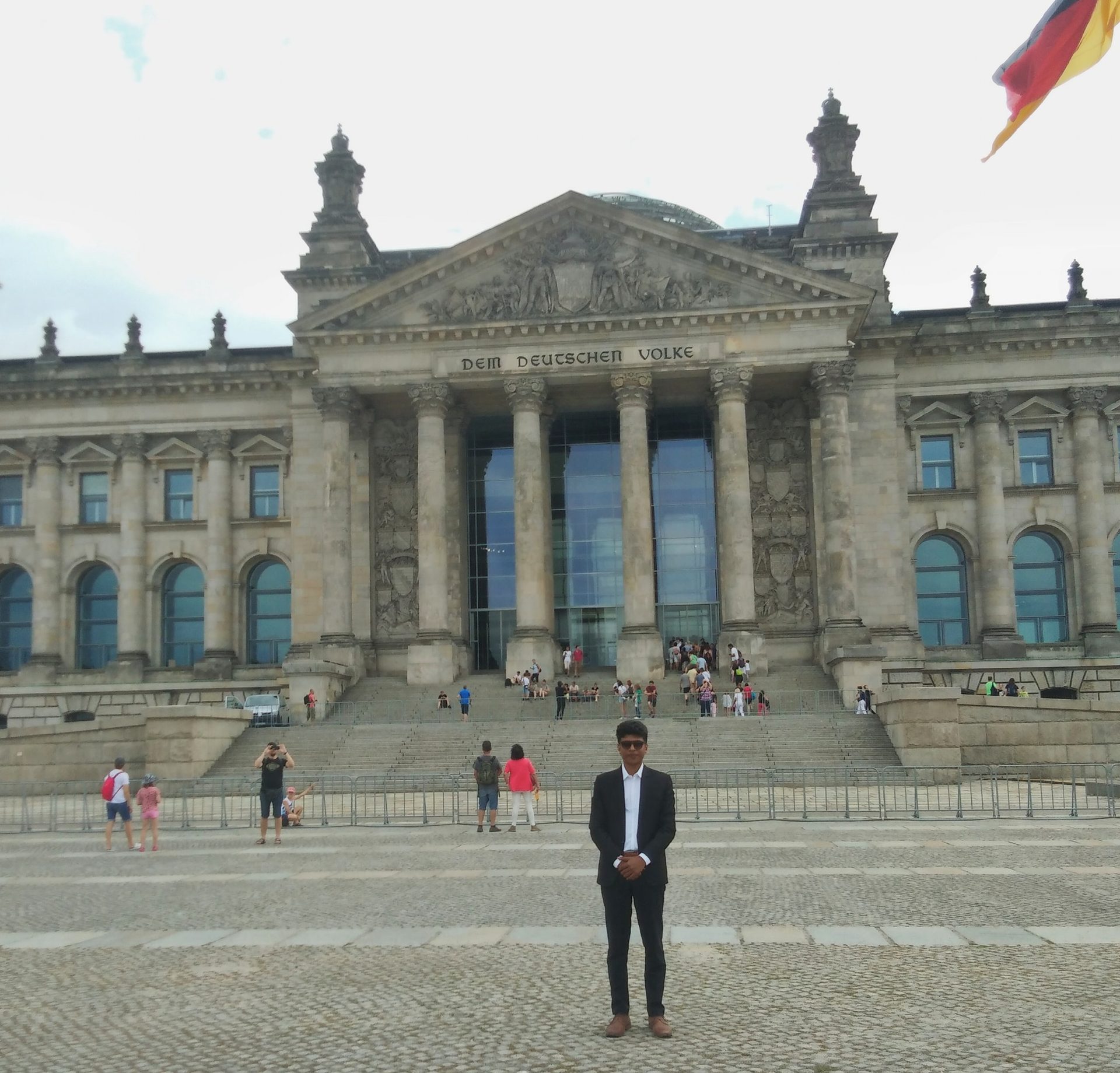 Raihan Khan standing before the main entrance of the Reichstag building, inscribed 'Dem Deutschen Volke,' in Berlin.