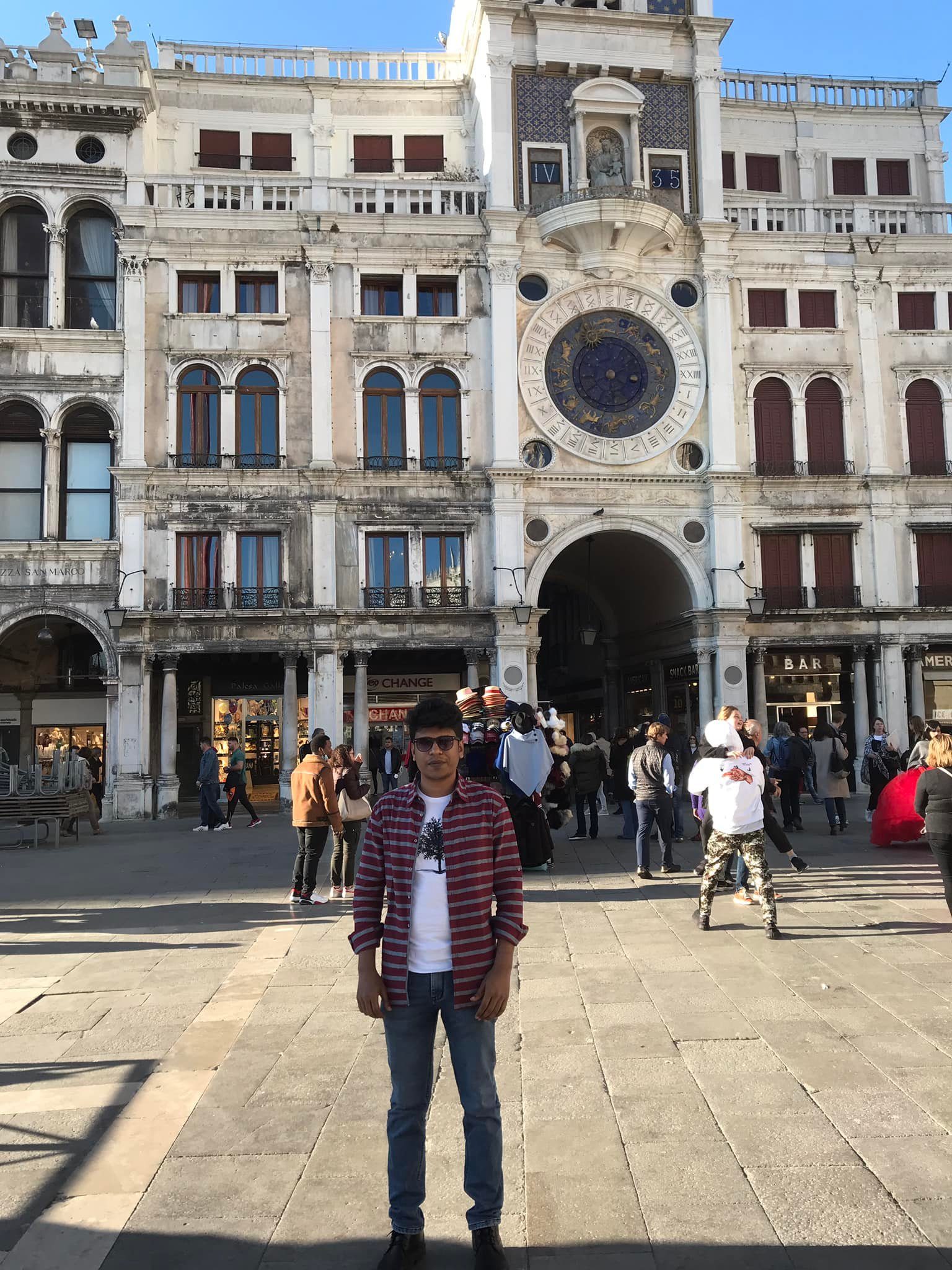 Raihan Khan standing in front of the astronomical clock tower in St. Mark's Square, Venice.