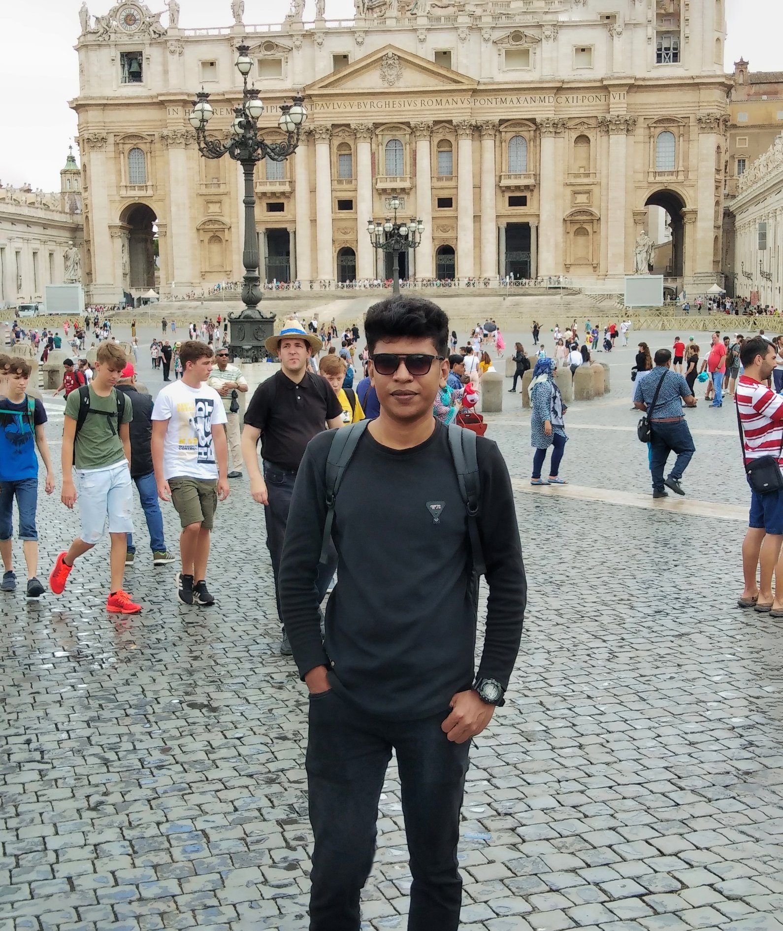 Raihan Khan standing in a crowded St. Peter's Square in front of St. Peter's Basilica during the day.